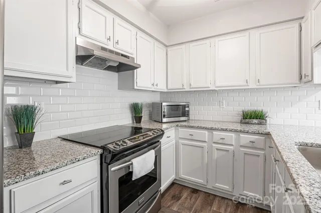 a kitchen with granite countertop white cabinets and white appliances