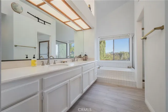 a spacious bathroom with a double vanity sink a mirror and a bathtub