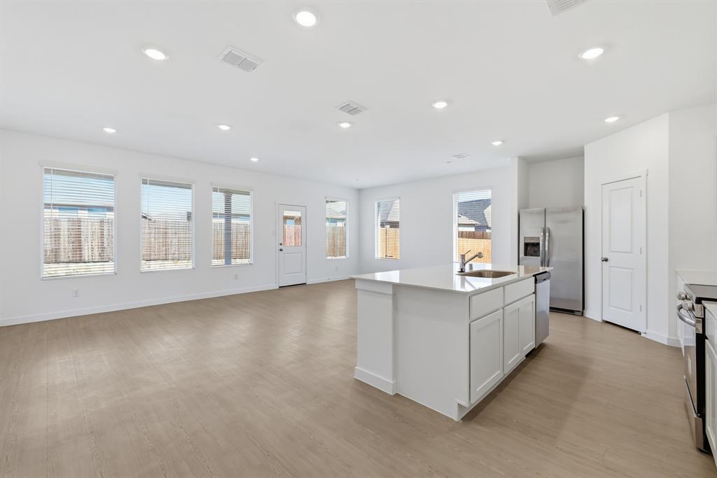 4912 Ascot Way Princeton, TX 75407 - Photo 9 of 35 a large white kitchen with kitchen island a sink a stove and a refrigerator