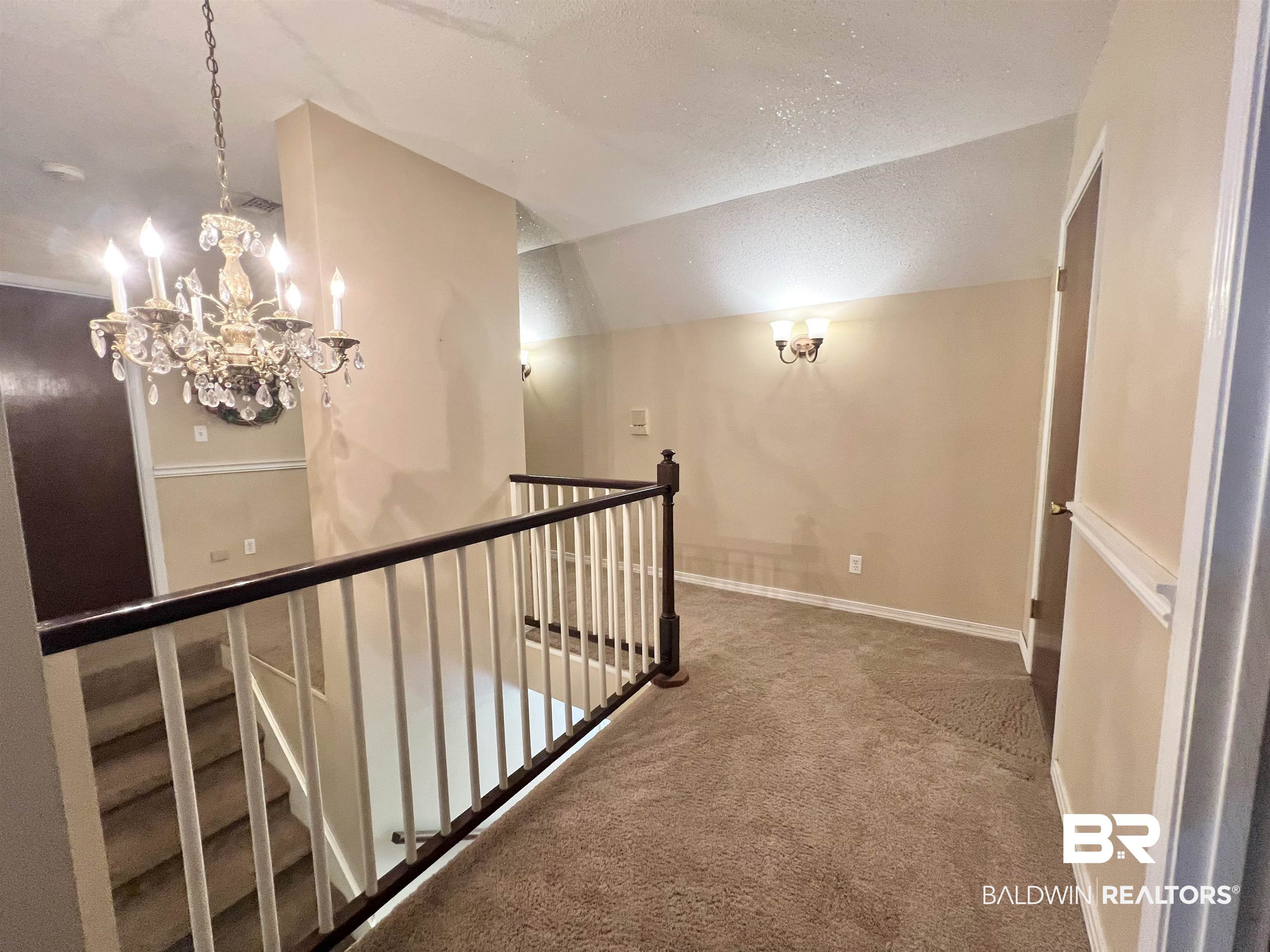 2691 Appleton Road Brewton, AL 36426 - Photo 31 of 60 Hallway featuring a textured ceiling, lofted ceiling, carpet floors, a chandelier, and an upstairs landing