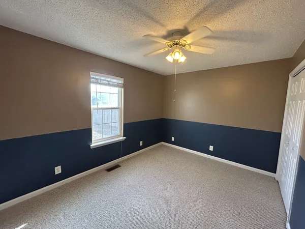 a view of an empty room with a chandelier fan
