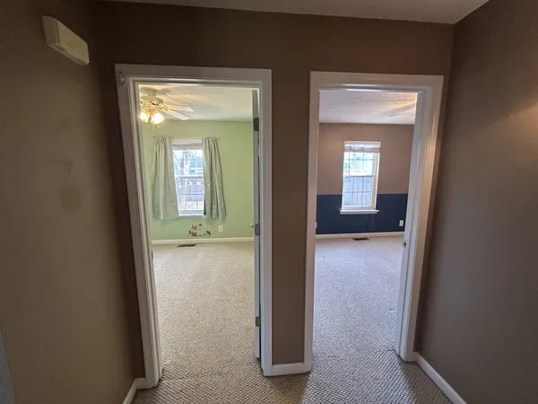 an empty room with a chandelier fan and windows