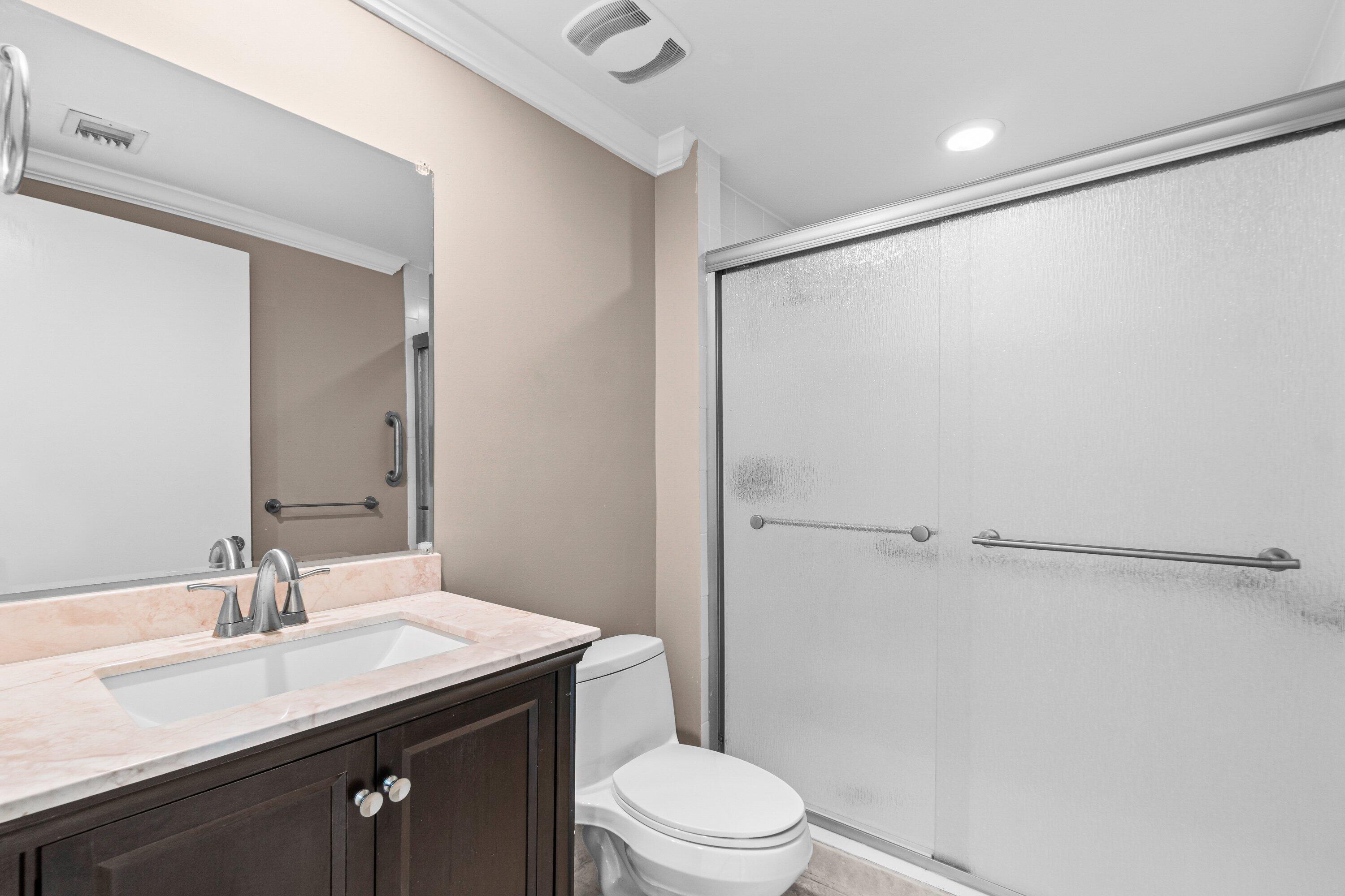 2650 Lake Shore Drive, Unit 703 Riviera Beach, FL 33404 - Photo 22 of 56 a bathroom with a sink a toilet a mirror and shower
