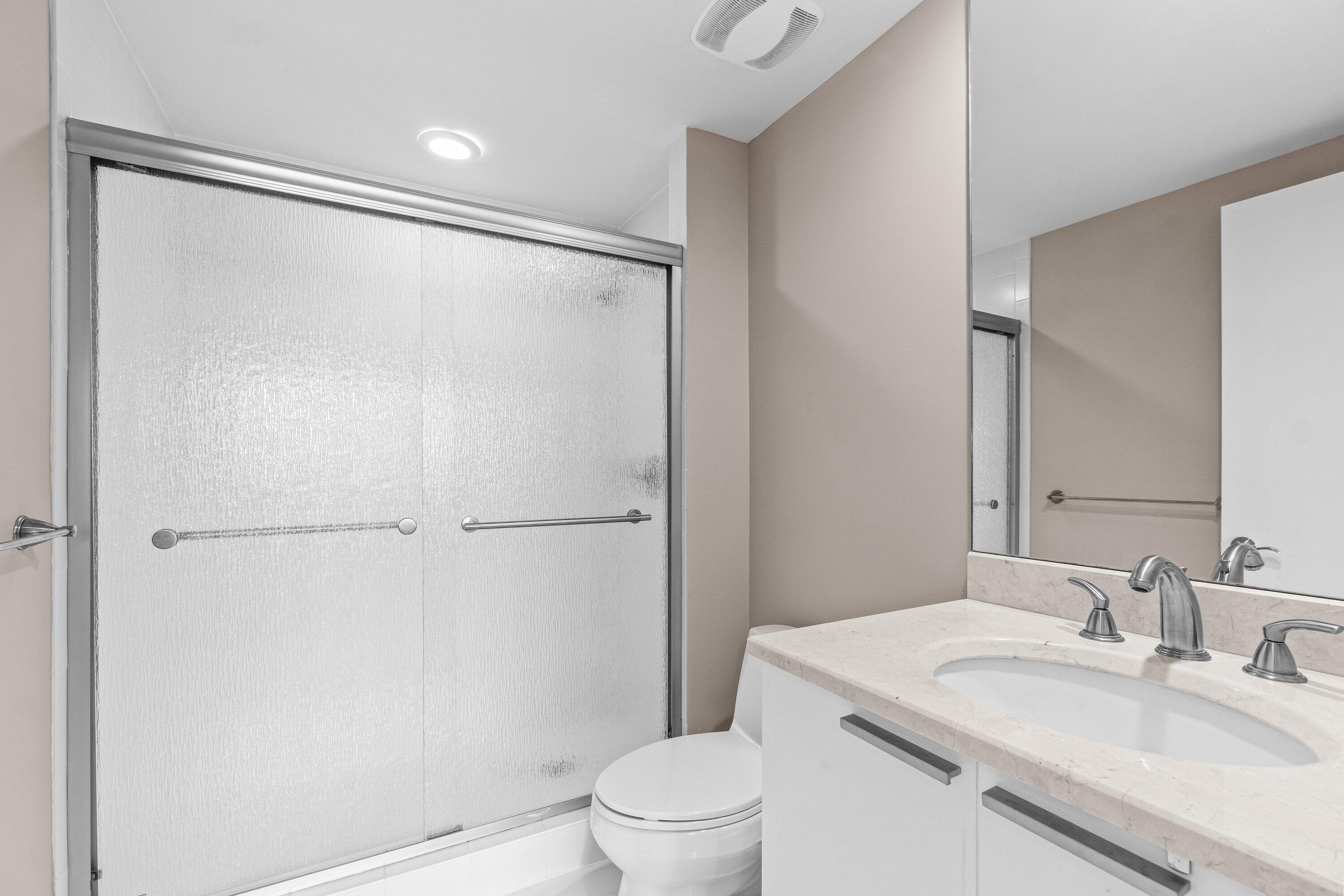 2650 Lake Shore Drive, Unit 703 Riviera Beach, FL 33404 - Photo 24 of 56 a bathroom with a granite countertop sink toilet and shower