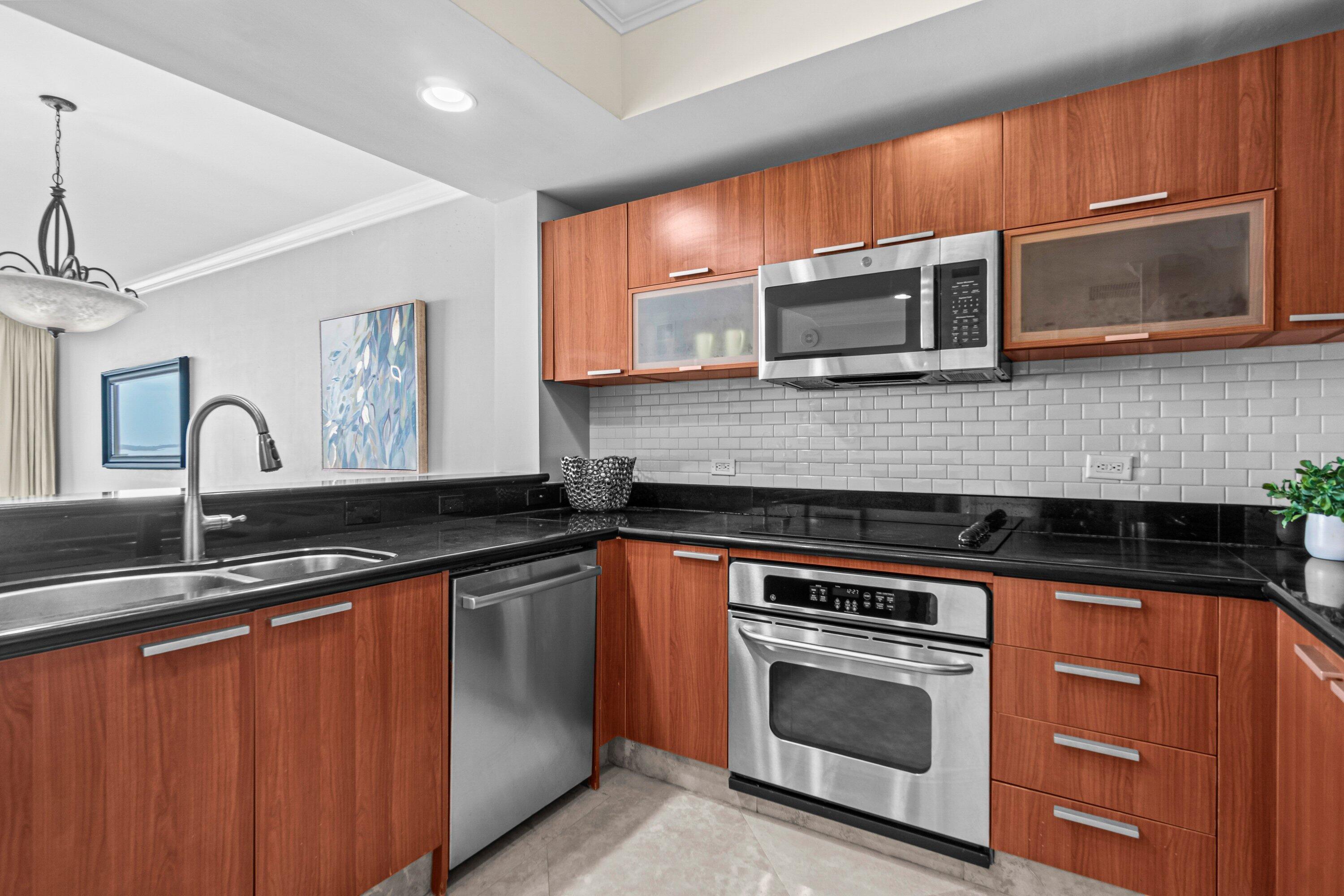 2650 Lake Shore Drive, Unit 703 Riviera Beach, FL 33404 - Photo 6 of 56 a kitchen with stainless steel appliances wooden cabinets and a stove top oven