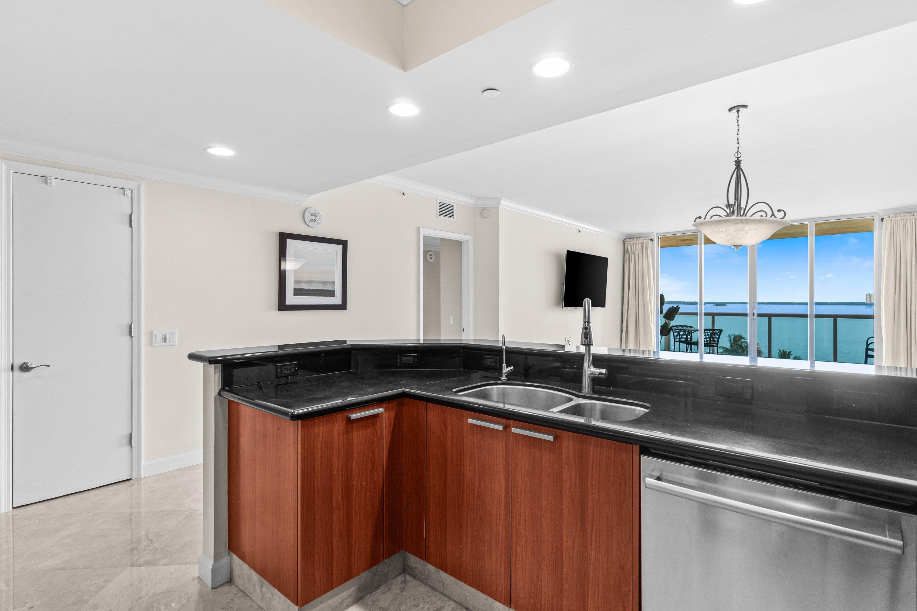2650 Lake Shore Drive, Unit 703 Riviera Beach, FL 33404 - Photo 7 of 56 a kitchen with granite countertop a sink and cabinets