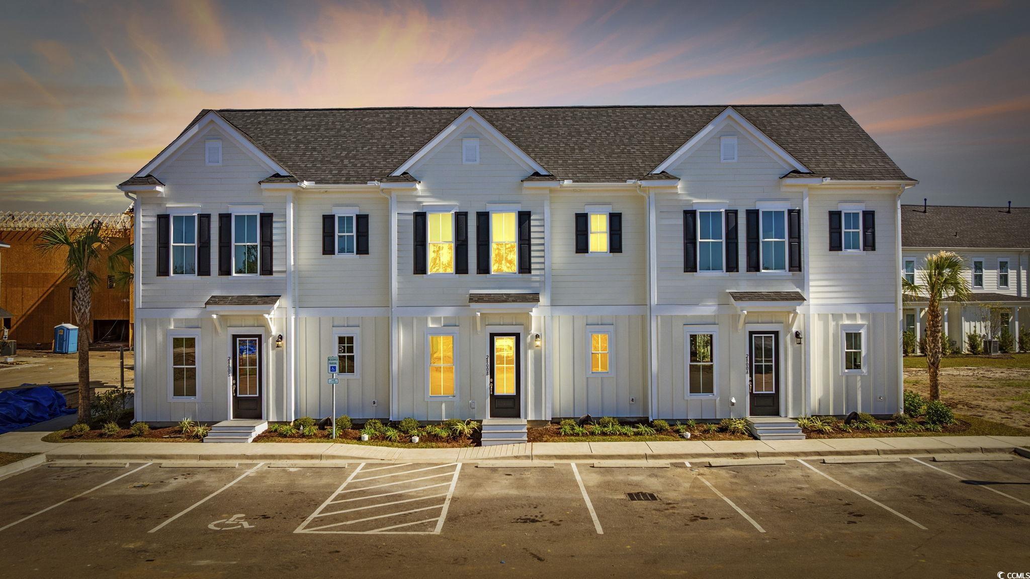 View of front of home with board and batten siding, uncovered parking, and a shingled roof