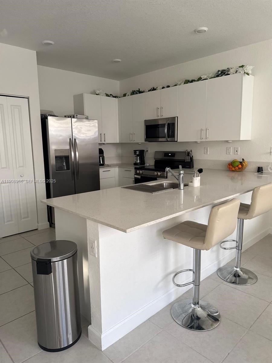 2894 Southeast 26th Terrace, Unit 1 Homestead, FL 33035 - Photo 3 of 11 a kitchen with stainless steel appliances granite countertop a sink refrigerator and microwave
