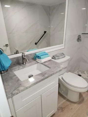 a bathroom with a granite countertop toilet sink and mirror