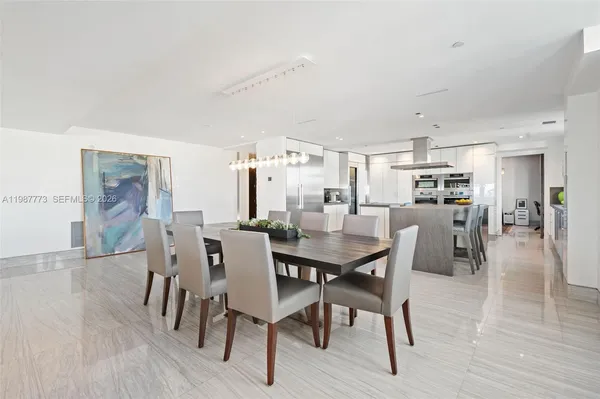 a kitchen with stainless steel appliances a refrigerator a stove top oven and a dining table with wooden floor