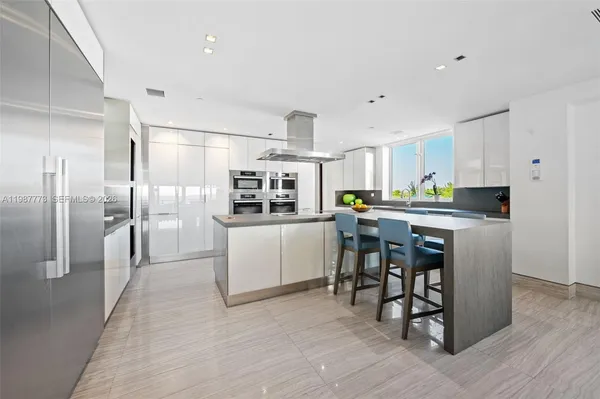 a kitchen with stainless steel appliances kitchen island granite countertop a refrigerator and a stove top oven