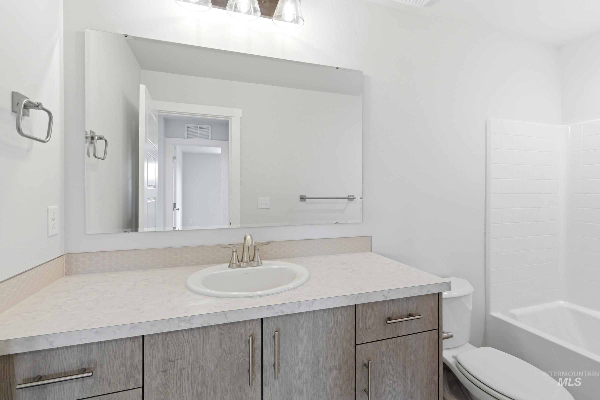 12829 Decatur Street Nampa, ID 83651 - Photo 23 of 33 Bathroom featuring a vanity with wood-finish cabinetry, a light-toned countertop, and an integrated sink