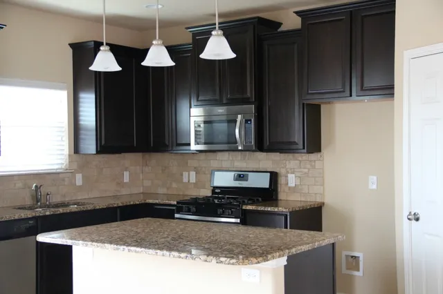 a kitchen with stainless steel appliances granite countertop a sink a stove and refrigerator