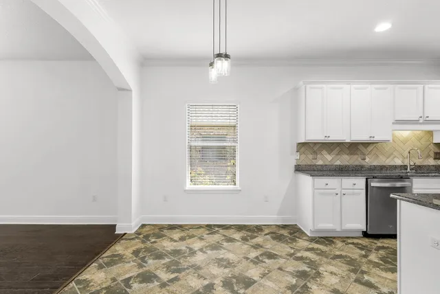 a kitchen with granite countertop a stove cabinets and wooden floor