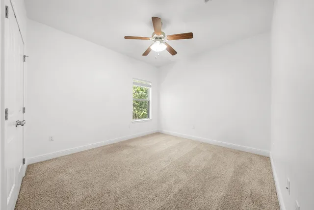 an empty room with windows and fan