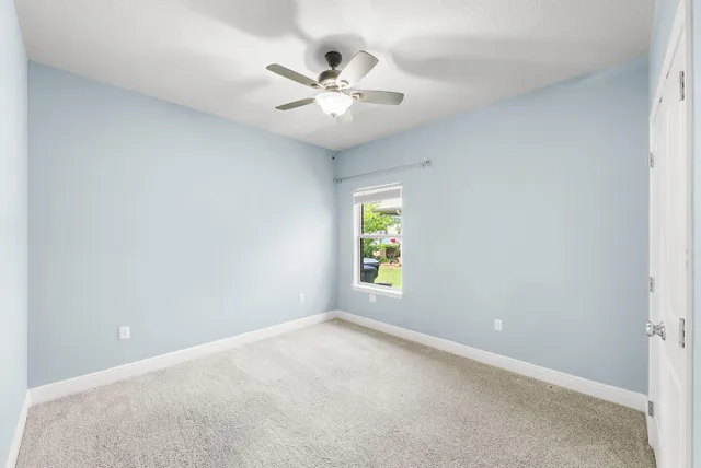 an empty room with window and ceiling fan