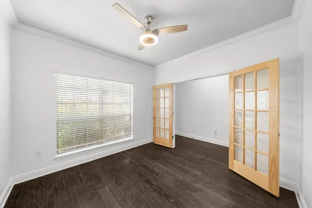 a view of an empty room with wooden floor and a window