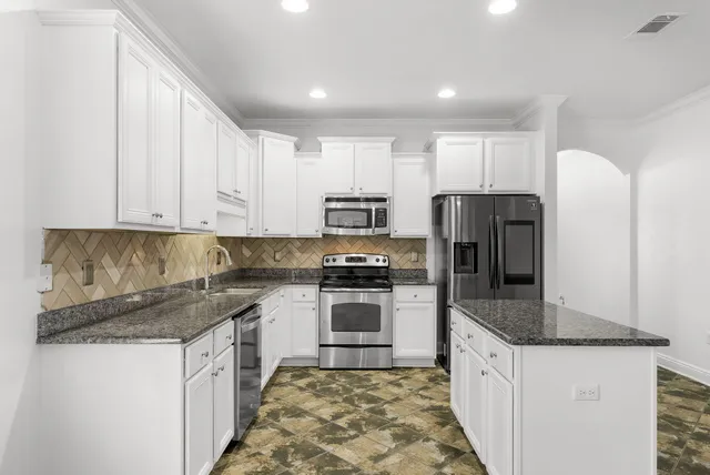 a kitchen with kitchen island granite countertop a sink stove and refrigerator
