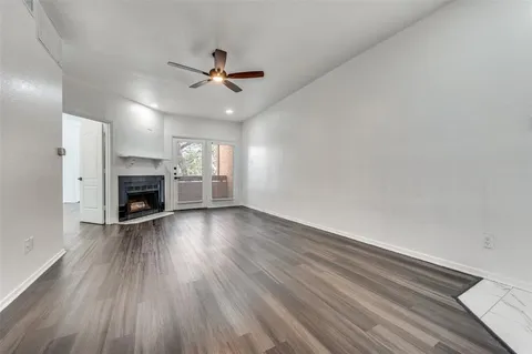 an empty room with wooden floor fireplace and windows