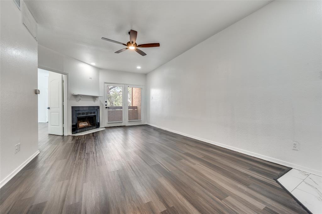 an empty room with wooden floor fireplace and windows