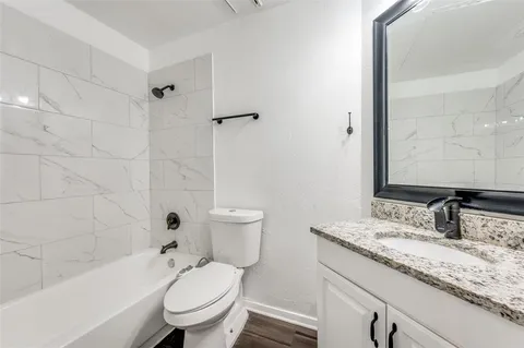a bathroom with a granite countertop sink a toilet and a bathtub