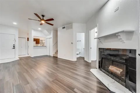 a view of a kitchen and an empty room with wooden floor a fireplace