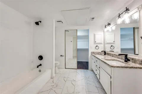 a bathroom with a granite countertop sink a mirror and a bathtub