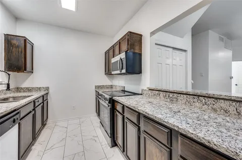 a kitchen with granite countertop a sink and a stove top oven