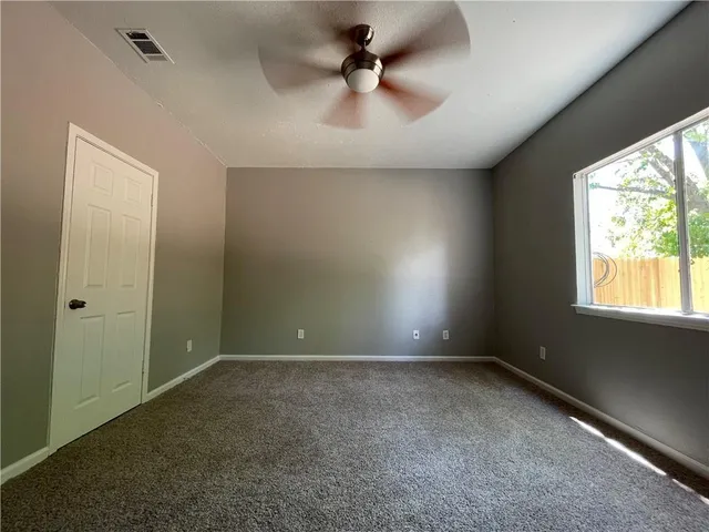 an empty room with windows and ceiling fan