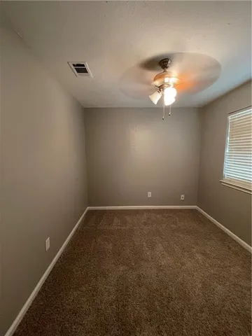 an empty room with a window and a ceiling fan