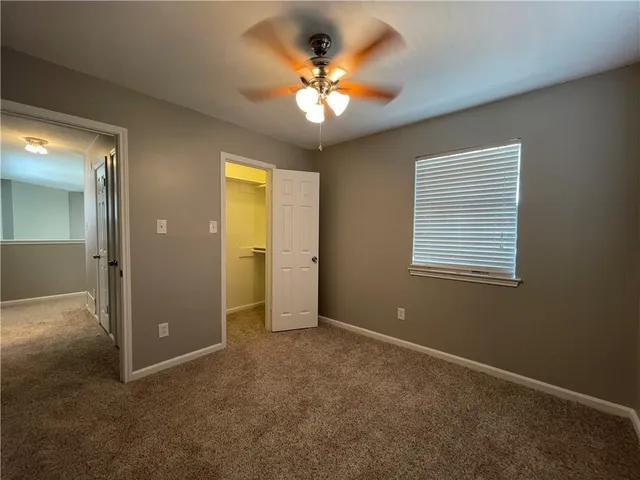 an empty room with a chandelier fan and windows