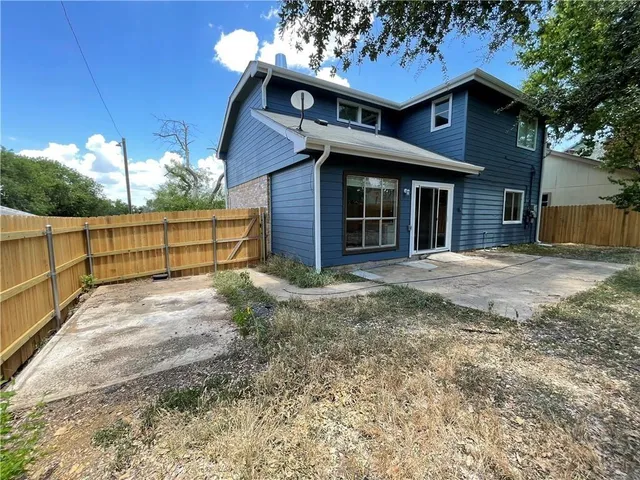 a view of a house with a yard and wooden fence