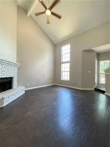 an empty room with wooden floor fireplace and windows