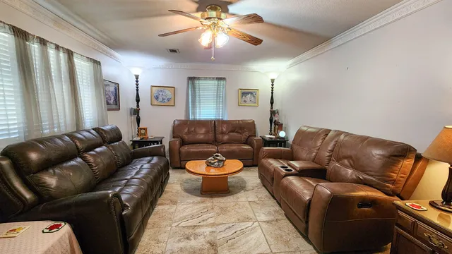 a living room with furniture a ceiling fan and a window