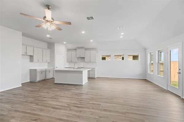 a kitchen with stainless steel appliances a sink dishwasher a refrigerator and white cabinets with wooden floor