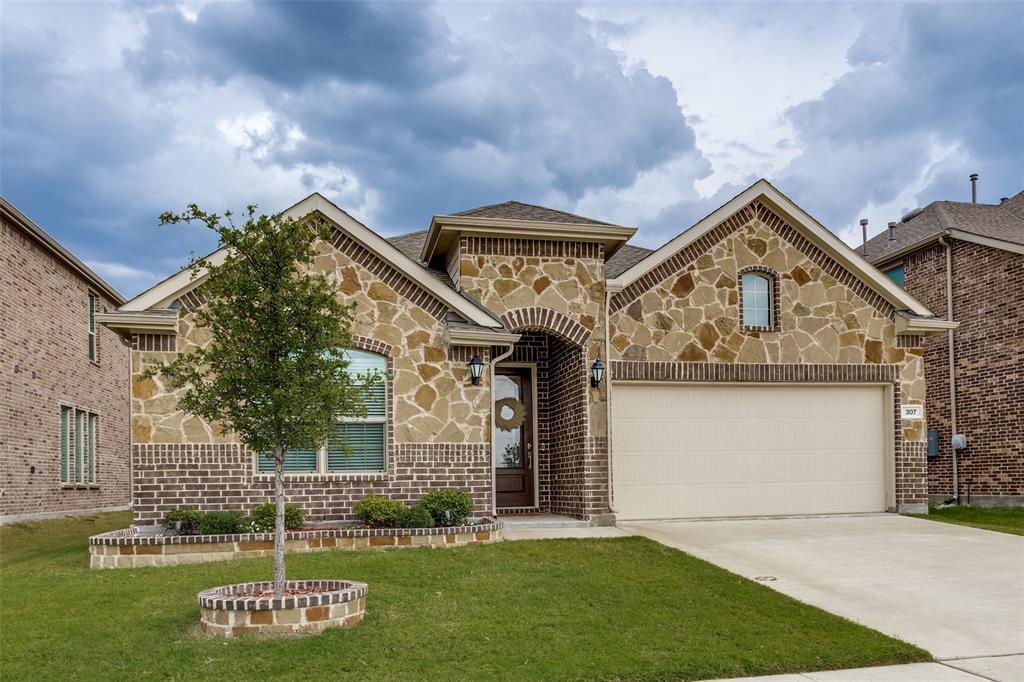 View of front of house with brick siding, stone siding, concrete driveway, and a front yard