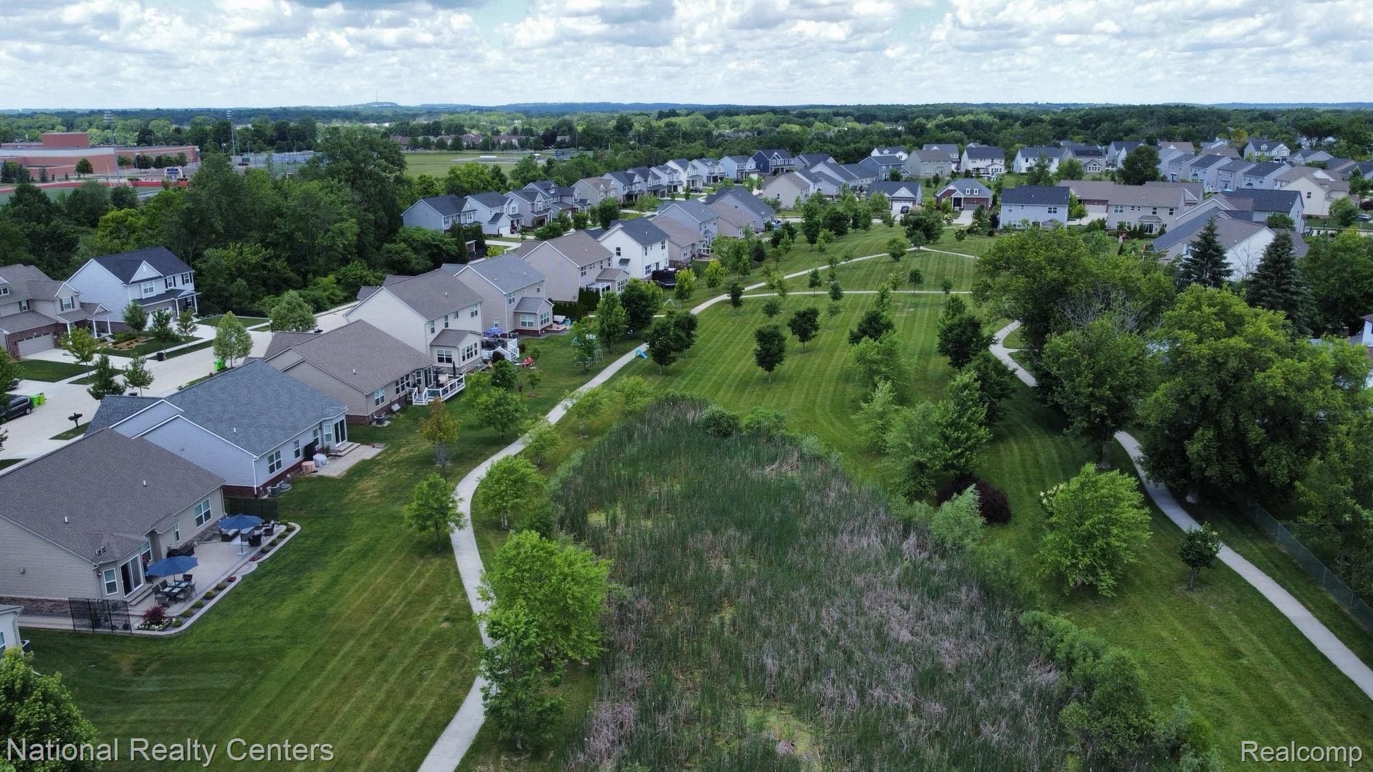 740 North Mill Street South Lyon, MI 48178 - Photo 5 of 56 Aerial perspective of a residential community featuring a variety of single-family homes with diverse architectural styles, surrounded by green spaces
