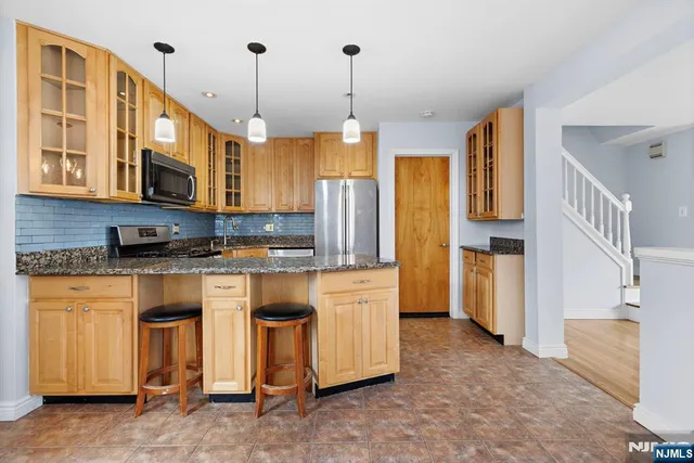 a kitchen that has a lot of cabinets in it and stainless steel appliances