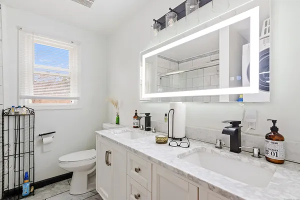 a bathroom with a granite countertop toilet sink and mirror