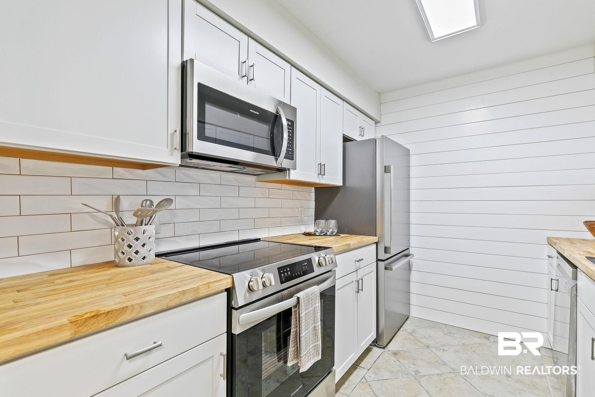 110 5th Street, Unit C103 Daphne, AL 36526 - Photo 18 of 46 Kitchen with white cabinets, stainless steel appliances, tasteful backsplash, and wooden counters