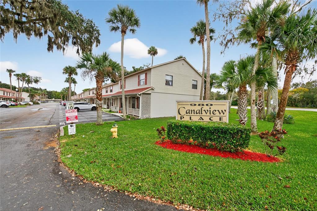 980 Canal View Boulevard, Unit J4 Port Orange, FL 32129 - Photo 2 of 25 a front view of a house with a big yard and large trees