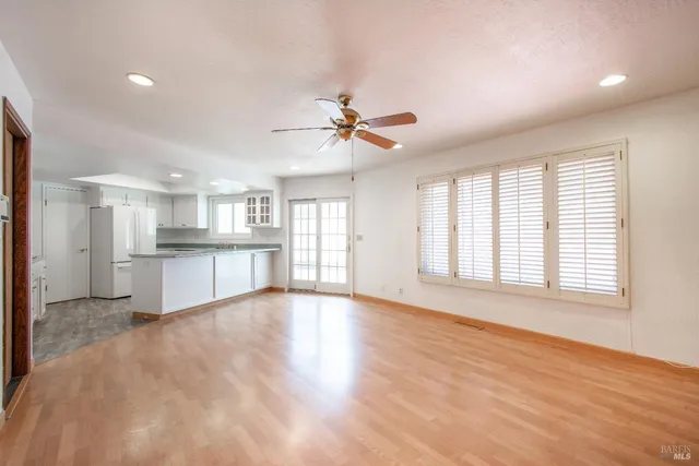 a view of an empty room with a kitchen and wooden floor