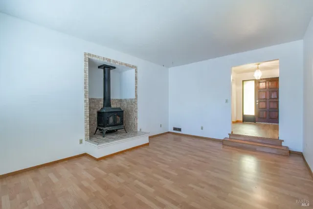 an empty room with wooden floor and a fireplace