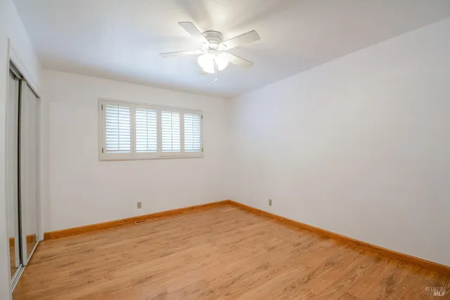 an empty room with a chandelier fan and windows