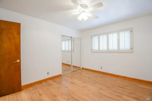 a view of empty room with wooden floor and fan