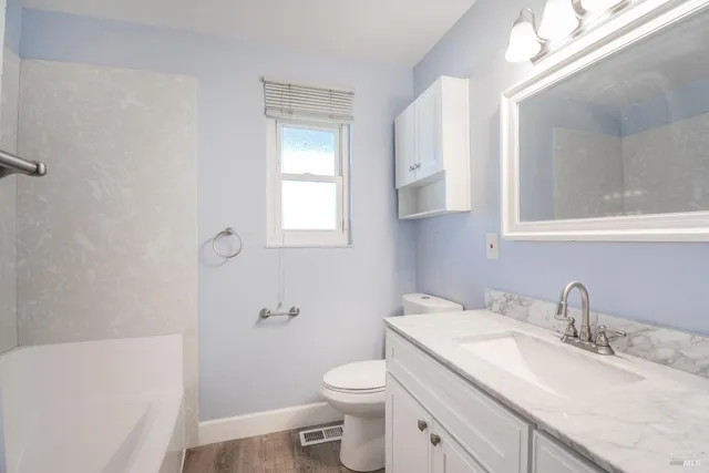 a bathroom with a granite countertop sink toilet and mirror
