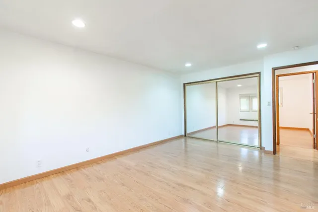 an empty room with wooden floor and natural light