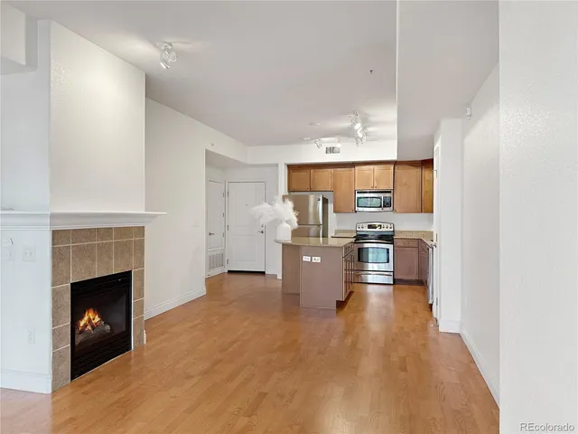 a kitchen with stainless steel appliances granite countertop a sink a stove top oven a refrigerator with wooden floors and cabinets