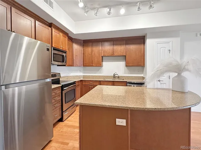 a kitchen with stainless steel appliances granite countertop a sink a stove a refrigerator a washer and dryer