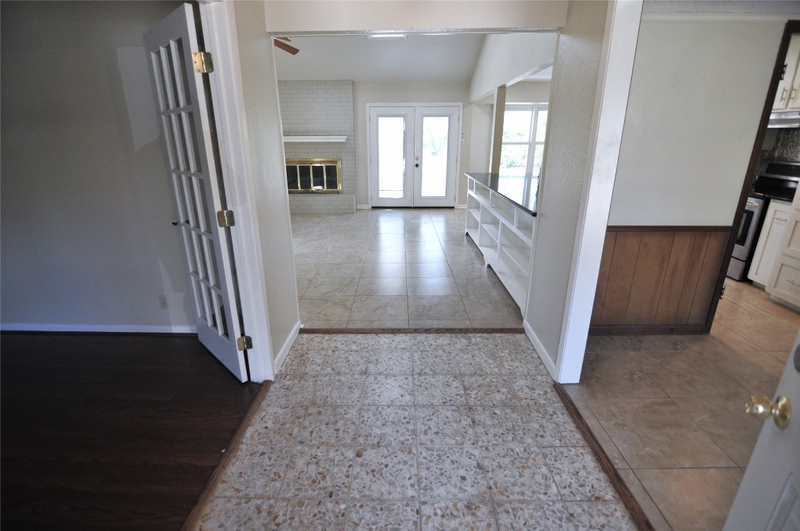 Hallway featuring french doors, light tile patterned flooring, and a wainscoted wall